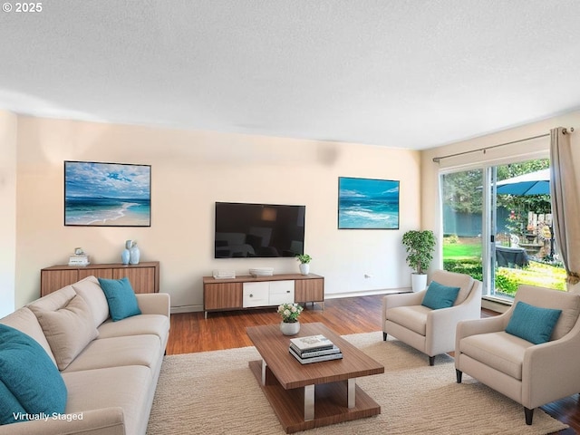 living area with wood finished floors, a textured ceiling, and baseboards