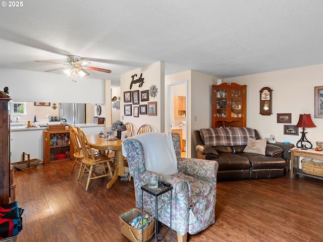 living room featuring wood finished floors, a ceiling fan, and a textured ceiling