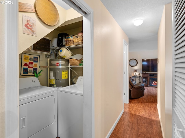 laundry room featuring separate washer and dryer, wood finished floors, strapped water heater, and baseboards