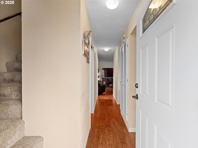 hallway featuring wood finished floors, stairs, and baseboards