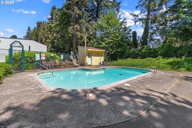 community pool with fence, view of scattered trees, and a patio area