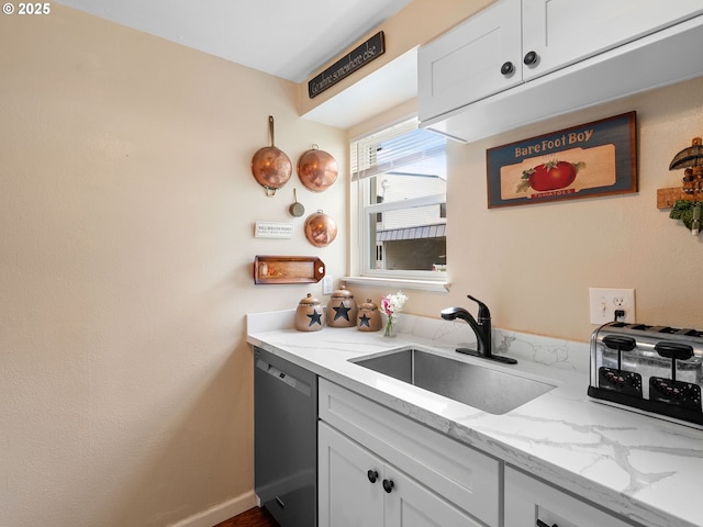 kitchen with stainless steel dishwasher, a sink, light stone counters, and white cabinetry