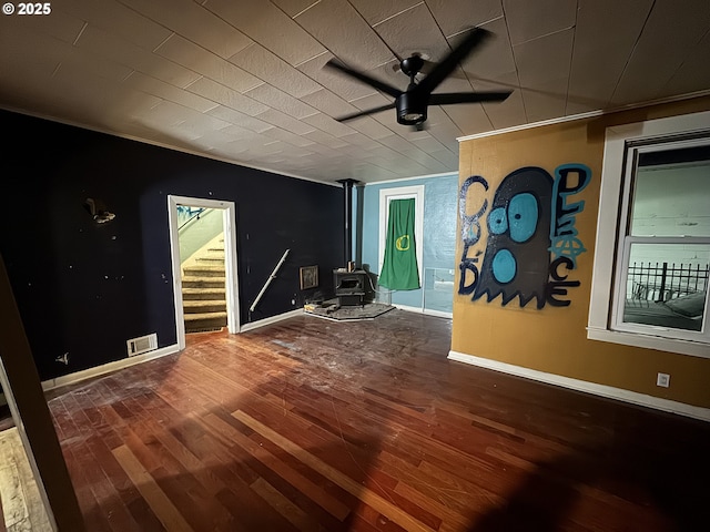 spare room with hardwood / wood-style flooring, a wood stove, and ceiling fan