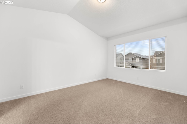 spare room featuring baseboards, carpet, and lofted ceiling