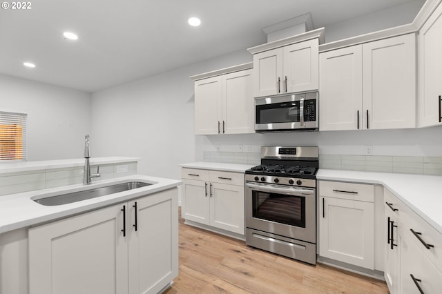 kitchen featuring a sink, light countertops, light wood finished floors, stainless steel appliances, and recessed lighting
