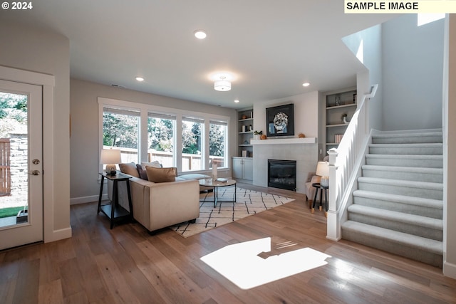 living area with plenty of natural light, wood finished floors, and a tile fireplace