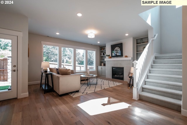 living room with recessed lighting, a tiled fireplace, and wood finished floors