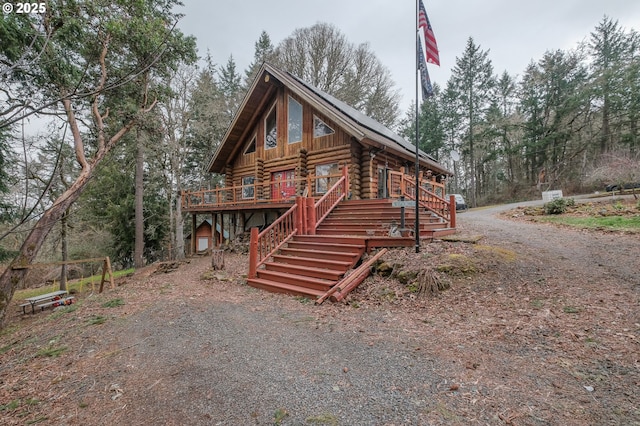 log-style house with a deck, driveway, stairway, and log siding