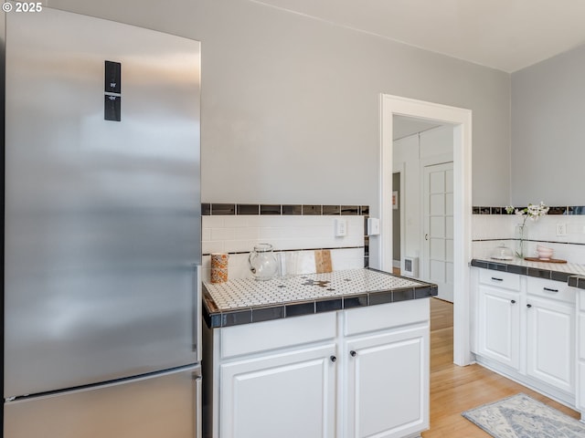 2015 NW Flanders St Unit 511, Portland, OR 97209 - kitchen with high end fridge, backsplash, white cabinetry, tile countertops, and light wood finished floors