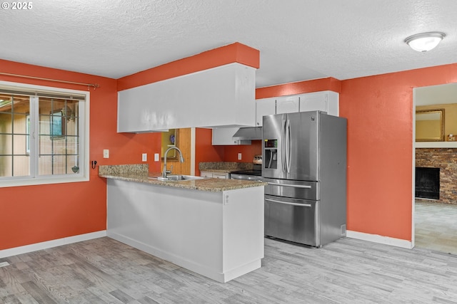 5715 SW 191st Ave, Beaverton, OR 97078 - kitchen featuring stainless steel appliances, under cabinet range hood, a textured ceiling, light wood finished floors, and a peninsula
