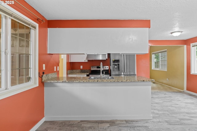 5715 SW 191st Ave, Beaverton, OR 97078 - kitchen with stainless steel fridge with ice dispenser, under cabinet range hood, light wood-style floors, light stone counters, and a textured ceiling