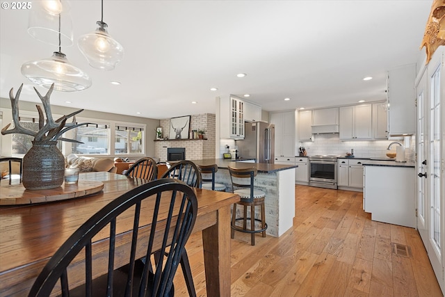 99 Walnut St, La Grande, OR 97850 - kitchen with stainless steel appliances, dark countertops, under cabinet range hood, light wood-style floors, and recessed lighting