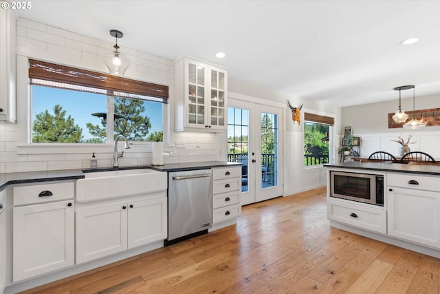 99 Walnut St, La Grande, OR 97850 - kitchen featuring stainless steel appliances, dark countertops, decorative backsplash, white cabinetry, and light wood-type flooring
