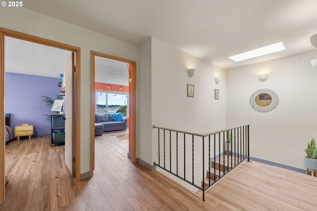 601 N Tomahawk Island Dr, Portland, OR 97217 - corridor featuring an upstairs landing, baseboards, wood finished floors, and a skylight