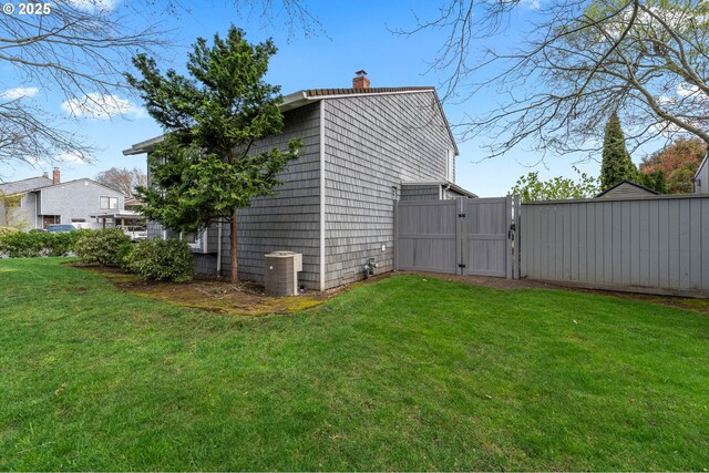 601 N Tomahawk Island Dr, Portland, OR 97217 - view of side of home with a yard, central AC, a gate, and a chimney