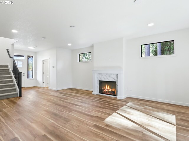 unfurnished living room with a healthy amount of sunlight, recessed lighting, baseboards, and stairs