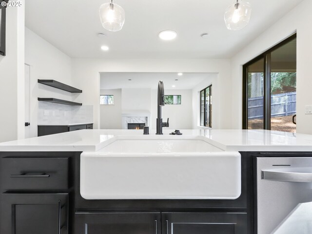 kitchen featuring light countertops, hanging light fixtures, a sink, and a fireplace