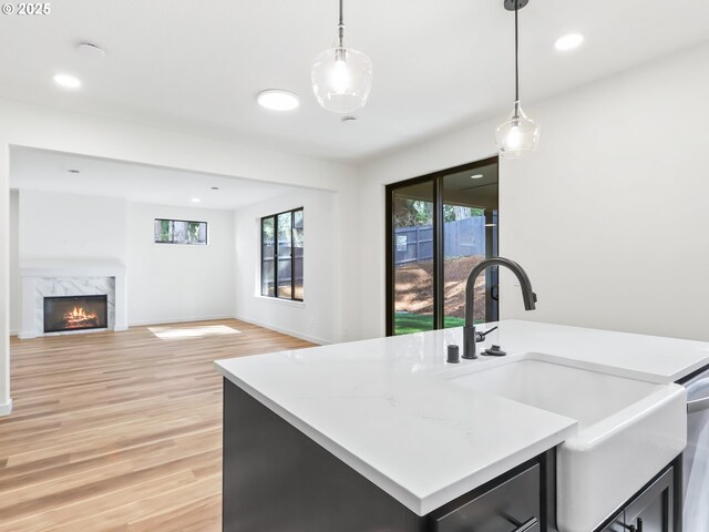 kitchen with light countertops, decorative light fixtures, a sink, and light wood-type flooring