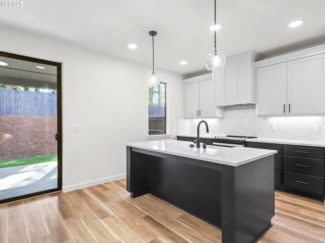kitchen with light countertops, plenty of natural light, a sink, and an island with sink