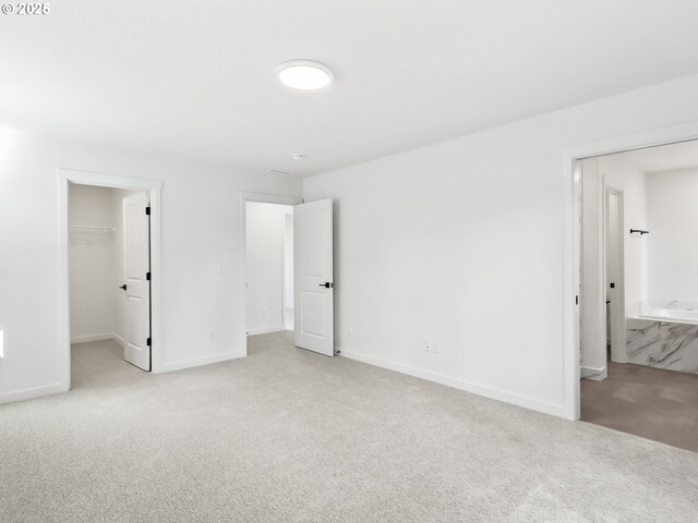 unfurnished bedroom with a closet, baseboards, carpet flooring, and a spacious closet