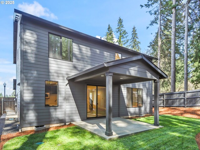 back of house with fence, a yard, and a patio area