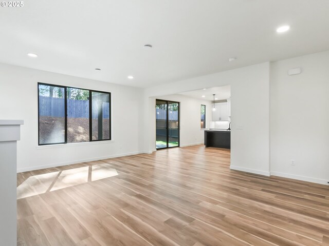 unfurnished living room featuring recessed lighting, plenty of natural light, and light wood-style flooring
