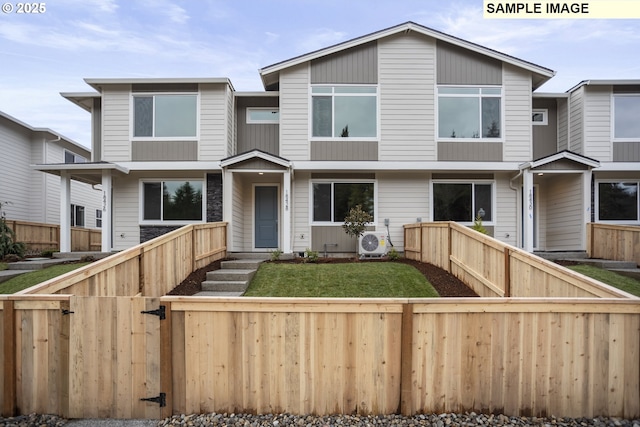 townhome / multi-family property with ac unit, a fenced backyard, and a front yard