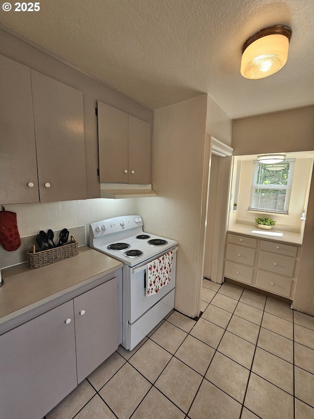 1760 W Broadway, Eugene, OR 97402 - kitchen with white electric range oven, under cabinet range hood, light countertops, light tile patterned floors, and a textured ceiling