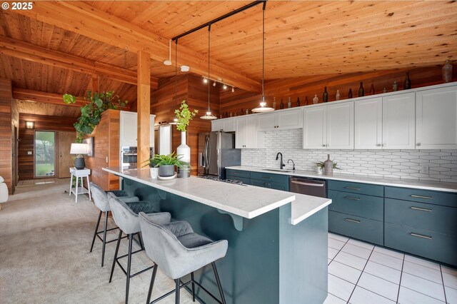 kitchen with wooden walls, a breakfast bar, stainless steel appliances, light countertops, and a sink