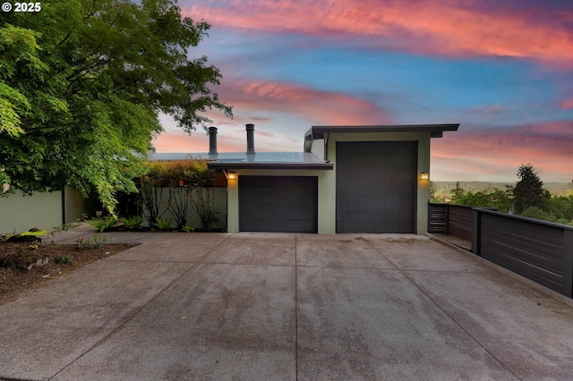 garage at dusk with fence and driveway