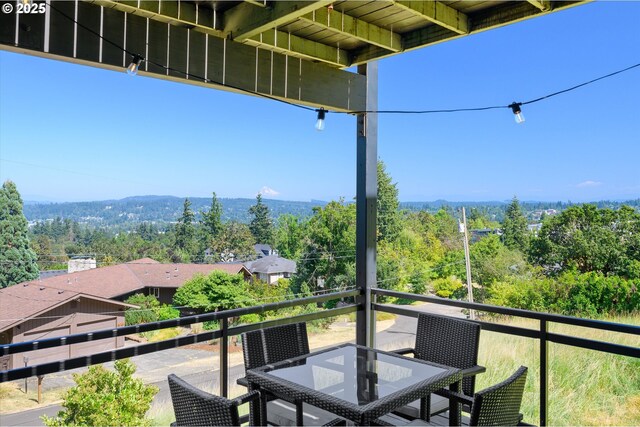 balcony with outdoor dining area and a wooded view