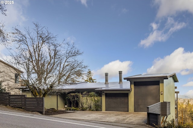 view of front of property featuring a garage, fence, and concrete driveway