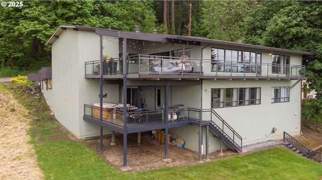 rear view of property featuring a lawn, a balcony, and stairs