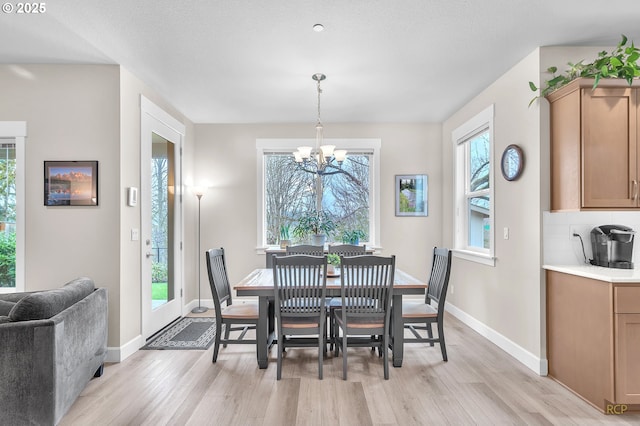 dining space featuring a chandelier, light wood-type flooring, and baseboards