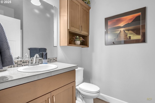 half bathroom featuring vanity, toilet, and baseboards