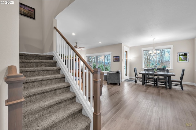 stairs featuring ceiling fan with notable chandelier, recessed lighting, wood finished floors, and baseboards