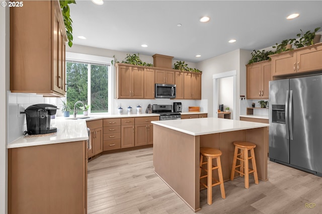 kitchen with a center island, light wood-type flooring, appliances with stainless steel finishes, and a sink