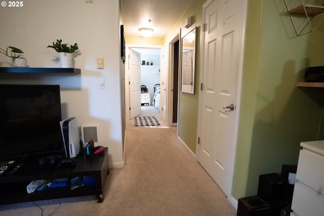 hallway featuring light colored carpet and a textured ceiling