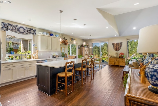 kitchen with a breakfast bar area, a center island, a sink, dark wood-style flooring, and light countertops
