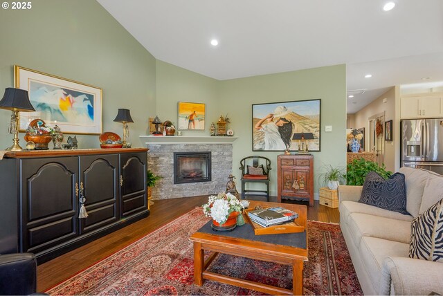living room with lofted ceiling, a stone fireplace, recessed lighting, and wood finished floors