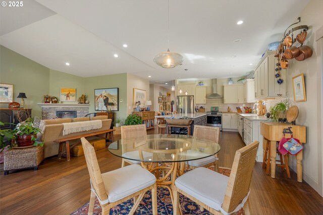 dining room with wood finished floors, recessed lighting, a fireplace, and vaulted ceiling