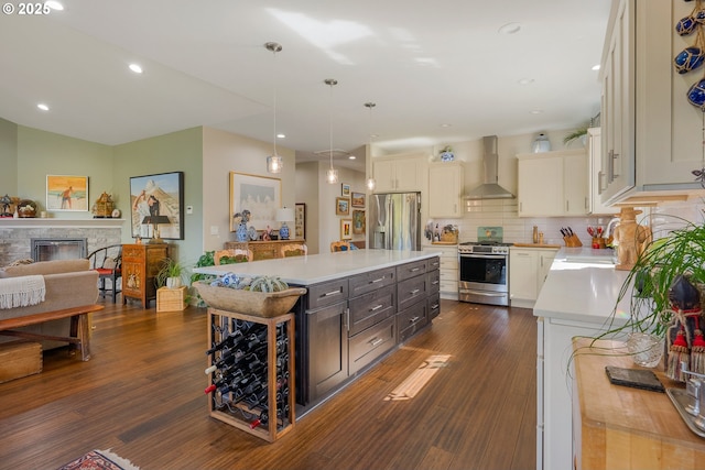 kitchen featuring decorative light fixtures, a sink, wall chimney exhaust hood, light countertops, and appliances with stainless steel finishes