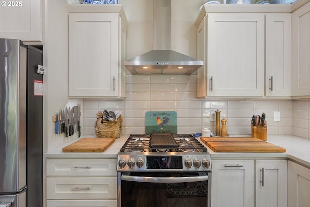 kitchen with light countertops, stainless steel appliances, white cabinetry, wall chimney range hood, and tasteful backsplash