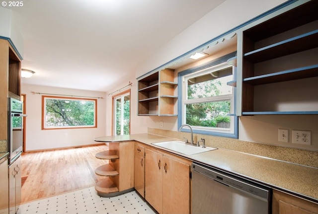 kitchen featuring open shelves, stainless steel appliances, a sink, light countertops, and light wood-type flooring