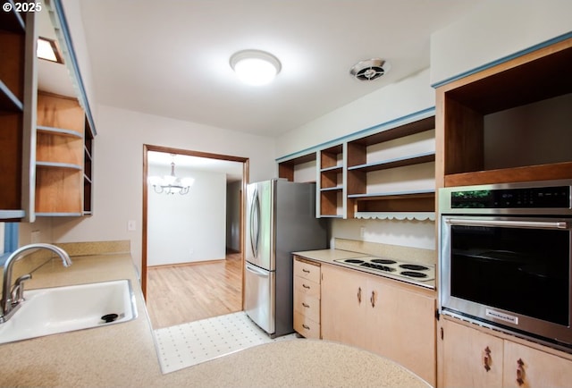 kitchen featuring open shelves, appliances with stainless steel finishes, a sink, and a chandelier