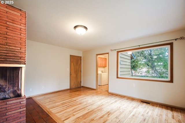 unfurnished living room featuring hardwood / wood-style flooring, washer / dryer, and baseboards