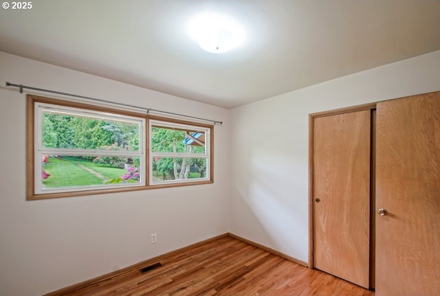 unfurnished bedroom with light wood-type flooring, a closet, and baseboards