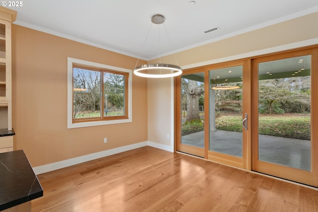 unfurnished dining area with light wood-type flooring, visible vents, and crown molding