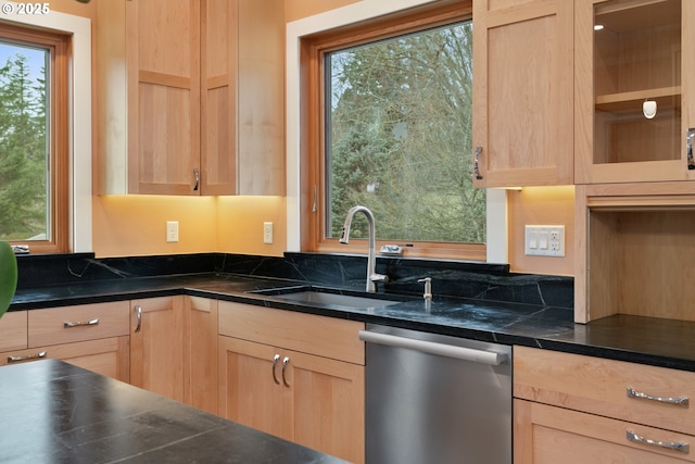 kitchen featuring dark countertops, dishwasher, a sink, and light brown cabinetry