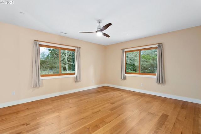 empty room featuring baseboards, ceiling fan, visible vents, and light wood finished floors